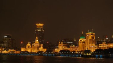 Shanghai Bund ve Lujiazui gece aydınlandı, ikonik gökdelenler, finansal bölge silueti, ve Huangpu Nehri üzerindeki göz kamaştırıcı yansımalar.