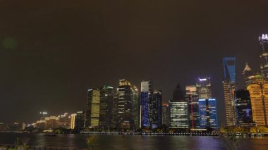 Shanghai Bund ve Lujiazui gece aydınlandı, ikonik gökdelenler, finansal bölge silueti, ve Huangpu Nehri üzerindeki göz kamaştırıcı yansımalar.