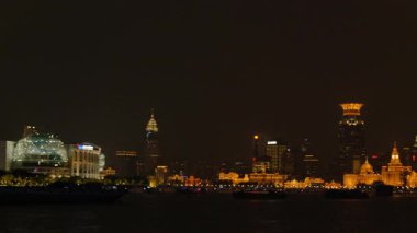 Shanghai Bund ve Lujiazui gece aydınlandı, ikonik gökdelenler, finansal bölge silueti, ve Huangpu Nehri üzerindeki göz kamaştırıcı yansımalar.