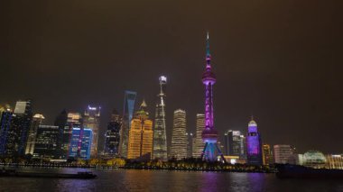Shanghai Bund ve Lujiazui gece aydınlandı, ikonik gökdelenler, finansal bölge silueti, ve Huangpu Nehri üzerindeki göz kamaştırıcı yansımalar.