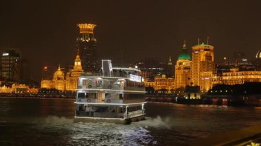 Shanghai Bund ve Lujiazui gece aydınlandı, ikonik gökdelenler, finansal bölge silueti, ve Huangpu Nehri üzerindeki göz kamaştırıcı yansımalar.