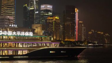 Shanghai Bund ve Lujiazui gece aydınlandı, ikonik gökdelenler, finansal bölge silueti, ve Huangpu Nehri üzerindeki göz kamaştırıcı yansımalar.