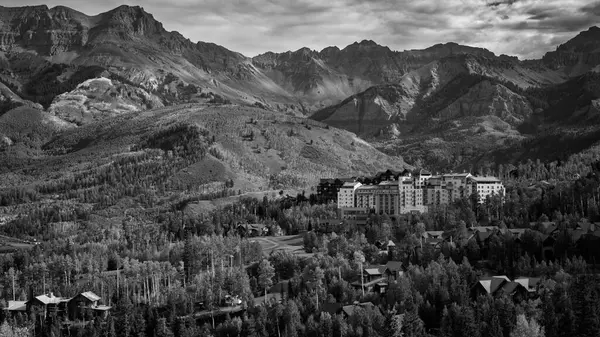 Dramatik bir siyah-beyaz manzara Telluride, Colorado 'nun engebeli tepelerini yakalar, aşağıdaki dağlık kasabada yükselir. Yüksek binalar, genişleyen orman ve sivri dağ silsilesiyle keskin bir tezat oluşturuyor..