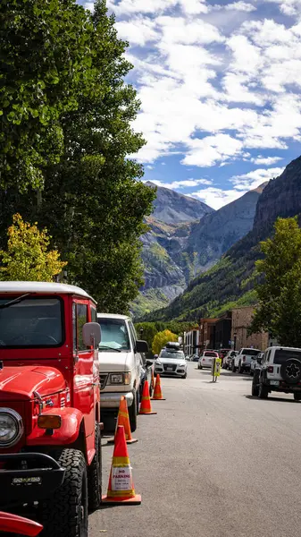 Çarpıcı kırmızı bir Toyota Land Cruiser, Colorado 'nun Telluride caddelerinde, nefes kesen Rocky Dağları zirveleri ve canlı bir sonbahar manzarasıyla park edilmiştir. Bu fotoğraf, bu tarihi dağ kasabasının maceraperest ruhunu yansıtıyor..