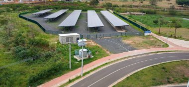 Güneş panelleri yeşil arazide düzenlenmiş bir güneş enerjisi istasyonunun hava görüntüsü, teknolojinin doğayla bütünleşmesini ve yenilenebilir enerjiye olan bağlılığını gösteriyor..