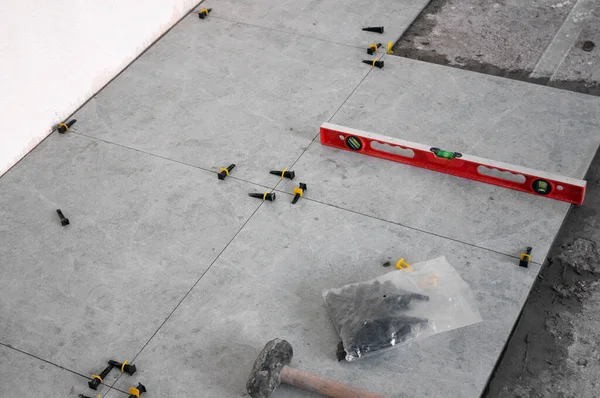 Alet ve eşyalar kullanarak yere döşeme işlemi. Gri fayanslar. Oda yenileme