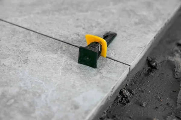 Alet ve eşyalar kullanarak yere döşeme işlemi. Gri fayanslar. Oda yenileme