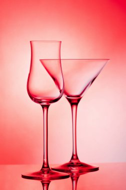 Kırmızı arka planda boş cam şarap kadehi.