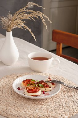 Immerse yourself in the morning freshness with fried tvorog pancakes, which are perfect for breakfast or afternoon snack. The light and tasty dish is served with mint leaves and bright pomegranate seeds, giving it freshness and visual appeal. Served  clipart