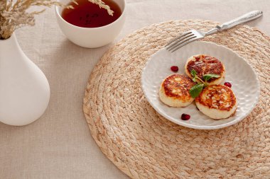 Immerse yourself in the morning freshness with fried tvorog pancakes, which are perfect for breakfast or afternoon snack. The light and tasty dish is served with mint leaves and bright pomegranate seeds, giving it freshness and visual appeal. Served  clipart