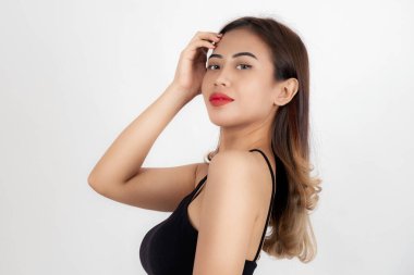 Siyah bluzlu, kendine güvenen genç bir kadının portresi beyaz arka planda saçına dokunuyor..