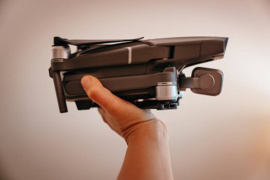 Bir insan elinde katlanmış bir dron tutar, kompakt tasarım gösterir ve hava içeriği oluşturmaya hazırdır..