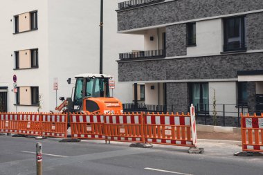 Gerresheimer caddesinde yeni yapılmış apartmanların önünde inşaat traktörü.