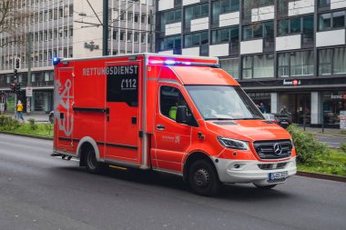 112 acil durum arabası şehrin merkezinde, Berliner Allee 'de mavi ışıklarla koşuyor.