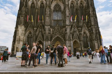 Köln katedralinin önündeki turistler manzaranın tadını çıkarıyorlar.