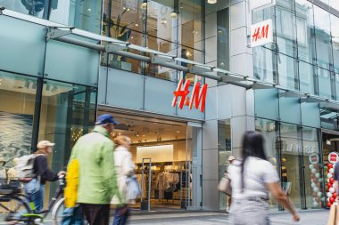 Cam cepheli H & M mağazası ve önde yürüyen insanlar