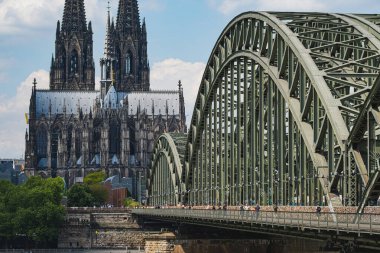 Arka planda Köln Katedrali olan Ren Nehri 'nden Hohenzollern Köprüsü' nü geçen insanlar.