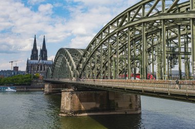 İnsanlar ve trenler, arka planda Köln Katedrali olan Ren Nehri 'nden Hohenzollern Köprüsü' nü geçiyor.