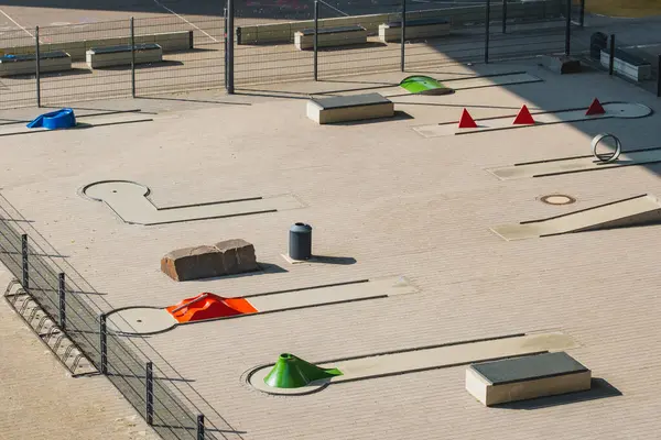 Açık hava mini golf sahasında renkli engeller ve hiç oyuncu yok.