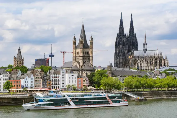 Colognes 'in renkli eski kasaba evleri, belediye binası ve arka planda ünlü Köln katedrali olan nehir manzarası.