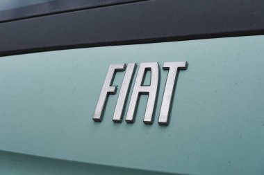 Fiat logo rozeti bir galerinin önündeki bir arabanın önünde.