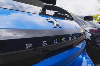 Peugeot logo rozeti bayiliğin dışında bir arabanın arkasında.