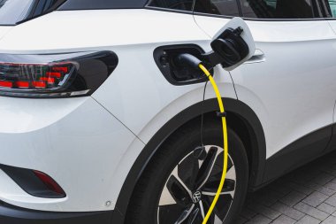 Şehrin kaldırımında sarı kabloyla elektrik yüklü bir araç.