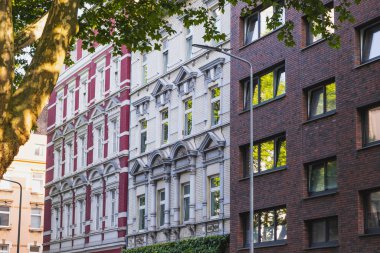 Yapraklı bir şehir sokağında renkli tarihi ve modern cepheler