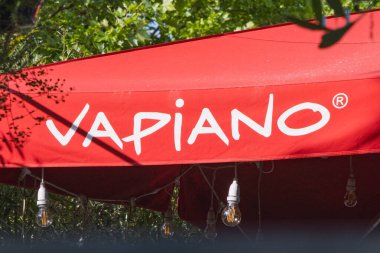 Vapiano logosu altında ışıklar asılı kırmızı bir gölgelik üzerinde