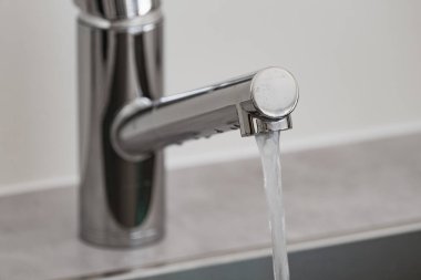 Modern krom musluktan akan su mutfak lavabosuna akıyor.