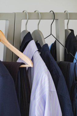 Çeşitli uniseks gömlekleri ve spor ceketleriyle minimalist giyim rafı.