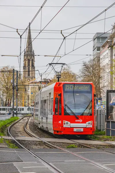 Şehir raylarında kırmızı tramvay. Arka planda kilise kulesi var.