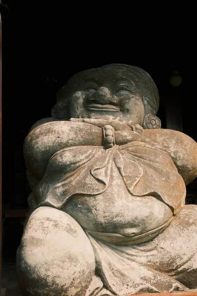 Bir Japon kamisi olan Daikokuten 'in yıpranmış taş heykeli, onun karakteristik neşeli ve yuvarlak şeklini gösteren yakın plan bir çekimde ele geçirilir.