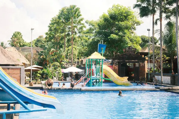 Kemenuh, Bali - 27 Nisan 2025 Bali 'deki Kemenuh Su Parkı' nda neşeli bir mavi yüzme havuzu ve suyun keyfini çıkaran çocuklar görülüyor.