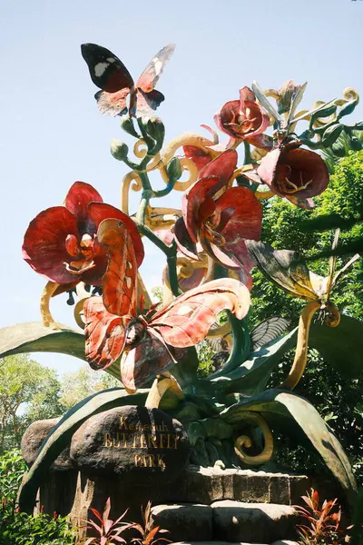 Kemenuh, Bali - 27 Nisan 2025: Kelebekler ve orkidelerin yer aldığı büyük, renkli bir heykel Kemenuh Kelebek Parkı 'nın önemli bir simgesi veya giriş süslemesi olarak hizmet vermektedir.