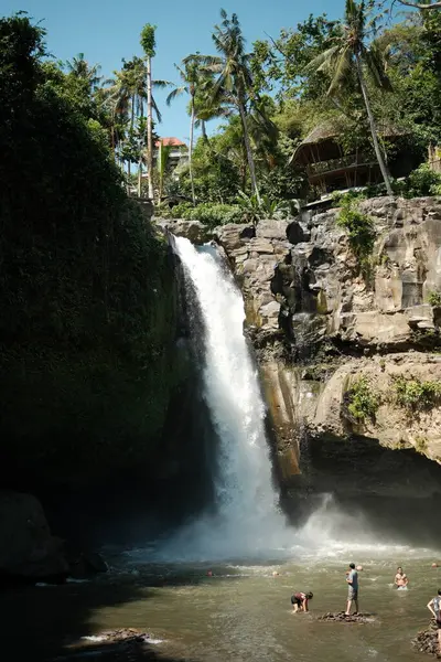 Tegenungan Şelalesi, Bali - 27 Nisan 2025: Çok sayıda turist şelalenin dibinde toplanarak suyun tadını çıkarıyor, fotoğraf çekiyor ve kayalık çevreyi keşfediyorlar.