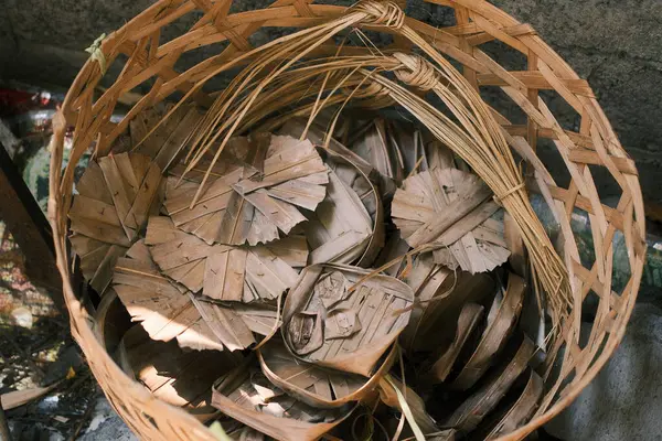 Çeşitli doğal, muhtemelen törensel, dokunmuş palmiye yapraklarından ya da benzer organik malzemelerden yapılmış kaplar, kadife çiçekleri ya da açık renkli yapraklar.