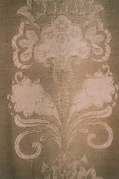 Süslü bir kumaşın, zarif, tek renkli bir renk paletinde, çiçekli, karışık desenli bir kumaşı, klasik zarafeti çağrıştırıyor.