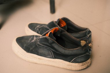 Bir çift esmer, beyaz tabanlı ve turuncu iç astarlı giysili ayakkabı, geniş kullanım belirtileri gösteriyor ve rahat, rahat bir tarzı var.