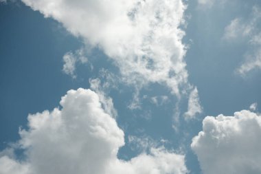 Canlı bir mavi gökyüzü, doğa, hava veya arka plan temaları için ideal, tüylü beyaz kümülüs bulutları dizisi için sakin bir zemin sağlar..