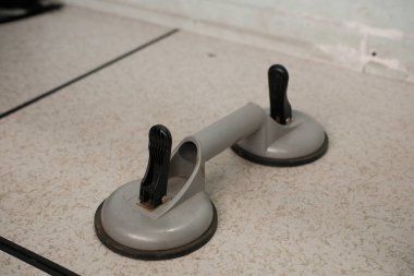 Siyah saplı ağır gri çift emici bir bardak kaldırıcı, cam veya diğer düz malzemeler için tasarlanmış hafif benekli bir yüzeye dayanır..