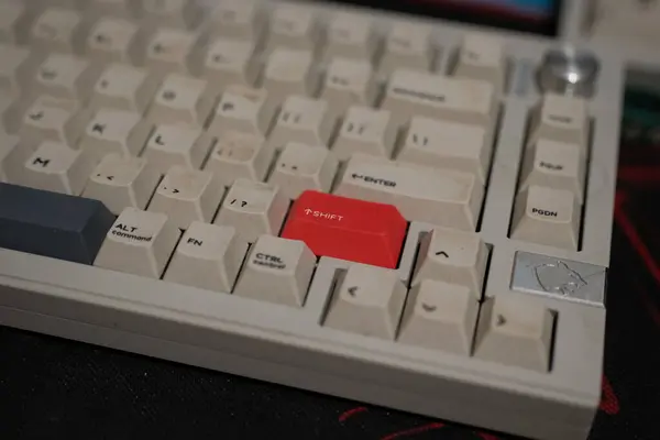 Sığ bir alan derinliği yakın çekim, bej mekanik klavyedeki kırmızı kaydırma tuşunu vurgular, anahtar başlıklarının dokusunu gösterir ve bulanık arkaplan ile etrafındaki düğmeleri gösterir