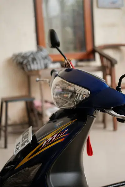 Denpasar, Bali - 07 Mayıs 2025: Mavi motosiklet mobiletinin ön kısmına odaklanan yakın çekim, farı, gidonu ve vücudun yumuşak bulanık arka planına dikkat çekiyor.