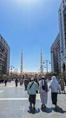 Medine, Suudi Arabistan - 6 Mart 2024: Seyyahlar, Hz. Muhammed el-Mecid an-Nabawi 'nin ana camisine dev şemsiyeler altında yürür ve namaz kılmaya hazırlanırlar..