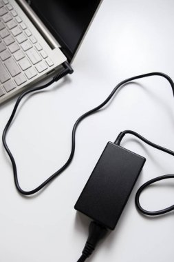 Güç adaptörüyle yüklenen dizüstü bilgisayar beyaz arkaplanda izole edildi