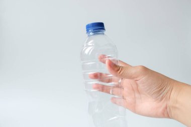 Beyaz arka planda plastik maden suyu şişesi tutan eller.