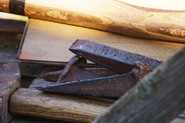 Ağaç parçalarının yanına yerleştirilmiş ağır ahşap işçiliği aletleri. Keskiler, çekiçler ve kalaslar atölyede görünür..