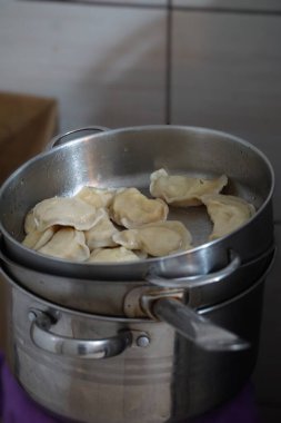 Geleneksel Rus usulü hamur tatlısı yapmak için elleri hamuru şekillendiriyor. Mantı hamuru hazırlama ve hamur köftesi oluşturma süreci açıkça gösteriliyor..