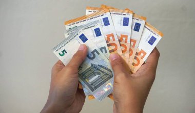 Kadınların elleri, dört adet 50 Euro 'luk banknot ve iki adet 5 Euro' luk banknotla çeşitli banknotlar halinde kullanıma hazır beyaz bir zemin hazırlıyor..