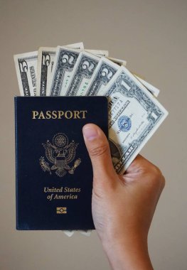 Sayfaların arasına Amerikan doları banknotları sıkıştırılmış açık bir Amerikan pasaportunun yakın çekimi. Belge ve paranın ayrıntılarını temizle.